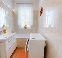 Badezimmer in einer 3-Zimmer-Wohnung mit Badewanne, Waschbecken, Waschmaschine und Fenster.