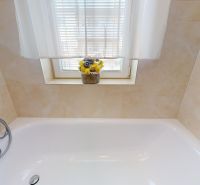 Badezimmer mit Duscharmatur, Badewanne und Blumen auf der Fensterbank in einer 3-Zimmer-Wohnung.