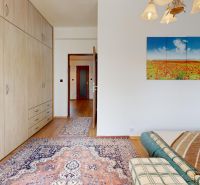 Schlafzimmer in einer 3-Zimmer-Wohnung mit Holzboden, Teppich und Bild an der Wand.