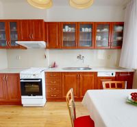 Küche in einer 3-Zimmer-Wohnung mit Holzschränken, Herd und Boden mit Holzdekor.