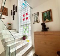 Schön beleuchtete Treppen mit Dekorationen, Kunstwerken und Blumen in einer 3-Zimmer-Wohnung.
