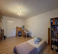 Ein Zimmer mit einem Schreibtisch, einem Bett und einem Boden in Holzoptik in einer 3-Zimmer-Wohnung.
