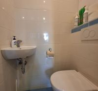 Die Toilette mit Waschbecken in der 3-Zimmer-Wohnung hat helle Fliesen.
