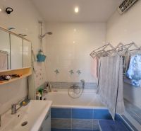 Badezimmer in einer 3-Zimmer-Wohnung mit Badewanne, Spiegelschrank und Fliesen.