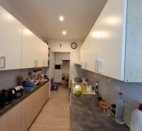 Küche in einer 3-Zimmer-Wohnung mit weißen Schränken und einem Boden in Holzoptik.