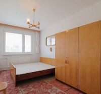 Schlafzimmer mit Bett, Schränken und Teppich in einer 2-Zimmer-Wohnung.