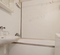 Badezimmer in einer 2-Zimmer-Wohnung mit Badewanne, Waschbecken und Waschmaschine.
