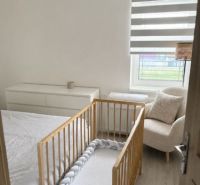Kinderzimmer mit einem Holzbett, hellen Möbeln und einem Sessel in einem Einfamilienhaus.