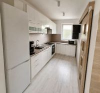 Eine Küche in einem Einfamilienhaus mit weißen Möbeln und einem hellen Boden in Holzoptik.