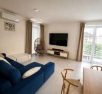 Helles Wohnzimmer in einem Einfamilienhaus mit einem blauen Sofa und einem Fernseher an der Wand.
