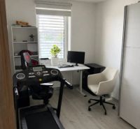 Heimbüro mit Laufband, Schreibtisch und Regal.