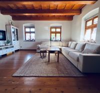 Wohnzimmer in einem Einfamilienhaus mit Sofa, Fernseher und Holzboden.