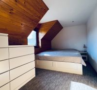 Dachbodenschlafzimmer in einem Einfamilienhaus mit Holzbalkendecke und Teppichboden.