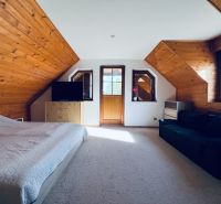 Ein Dachzimmer mit Holzelementen, einem Bett und einem Fernseher in einem Einfamilienhaus.