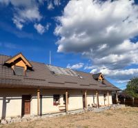 Ein Einfamilienhaus in Hronská Dúbrava mit einem großen Dach und einem steinigen Weg im Garten.