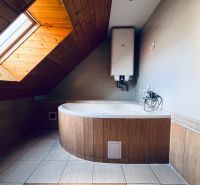 Dachbodenzimmer-Badezimmer mit Eckbadewanne und schräger Decke in einem Einfamilienhaus.