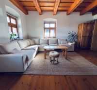 Wohnzimmer in einem Einfamilienhaus mit beigem Sofa und Boden in Holzoptik.