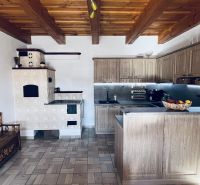 Eine Küche in einem Einfamilienhaus mit einem traditionellen Ofen und Holzbalkendecke.