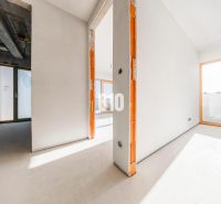 Geräumiges Interieur einer unvollendeten 3-Zimmer-Wohnung mit großen Fenstern und Betondecke.