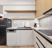 Küche in einer Einzimmerwohnung mit Holzboden und einem schwarzen Kühlschrank.