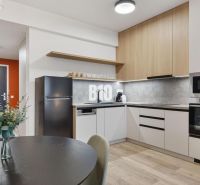 Küche mit Esstisch, Geräten und Holzboden in einer Einzimmerwohnung.