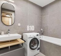 Badezimmer mit Waschbecken, Waschmaschine und Badewanne in einer Einzimmerwohnung.