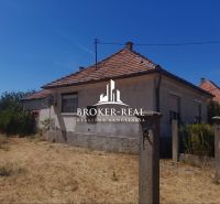 Ein Einfamilienhaus in Csobád mit verputzten Wänden, einem Ziegeldach und einer vernachlässigten Umgebung.