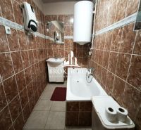 Ein Badezimmer in einem Einfamilienhaus mit braunen Fliesen und einer Badewanne.
