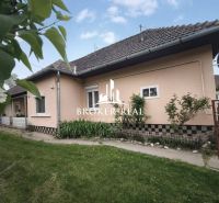 Ein Einfamilienhaus in Bódvaszilas mit hellen Wänden, einem schrägen Dach und einem grünen Rasen.