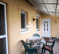Die Terrasse eines Einfamilienhauses in Bódvaszilas mit einem Tisch und Plastikstühlen auf einem gepflasterten Boden.