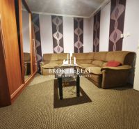 Wohnzimmer in einem Einfamilienhaus mit gestreiftem Sofa und bunter Tapete.