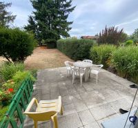 Der Garten eines Einfamilienhauses in Zvončín mit einer befestigten Terrasse, Stühlen und grünen Pflanzen.