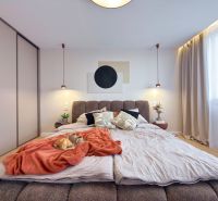 Schlafzimmer in einer 3-Zimmer-Wohnung mit Bett, Vorhängen und Schrank; Boden mit Holzdekor.