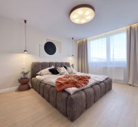 Helles Schlafzimmer mit großem Bett und Holzboden in einer 3-Zimmer-Wohnung.