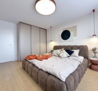 Schlafzimmer in einer 3-Zimmer-Wohnung mit einem großen Bett und einem Boden in Holzoptik.