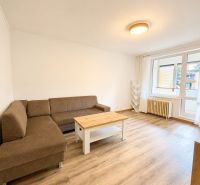 Wohnzimmer in einer 3-Zimmer-Wohnung mit Sofa, Couchtisch und Boden in Holzoptik.