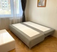 Einzimmerwohnung mit Bett, Holzboden und weißem Tisch.