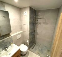 Kompaktes Badezimmer in einem Studio-Apartment mit offener Dusche und Fliesen.