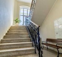 Eine Treppe mit einem Metallgeländer und einer Bank in einem Büro, beleuchtet durch ein großes Bogenfenster.