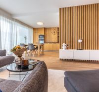 Wohnzimmer in einem Einfamilienhaus mit Holzboden und Essbereich im Hintergrund.