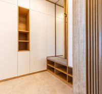 Flur in einem Einfamilienhaus mit Möbeln, Sitzgelegenheit und Wandverkleidung aus Holz.
