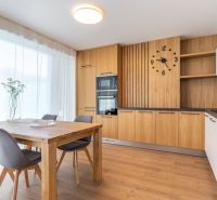 Küche mit Holzdekor, Esstisch, grauen Stühlen und großen Fenstern.