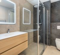 Ein Badezimmer mit Holzmöbeln, einer Duschkabine und einem großen Spiegel in einem Einfamilienhaus.