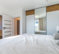 Ein Schlafzimmer in einem Einfamilienhaus mit einem großen Einbauschrank und einem Bett in hellen Farben.