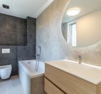 Badezimmer in einem Einfamilienhaus mit Badewanne, Waschbecken und Fliesen in dunklen Tönen.