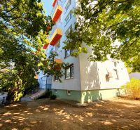 Ein Wohnblock mit bunten Balkonen in der Straße Lúky in Vráble, umgeben von Bäumen.