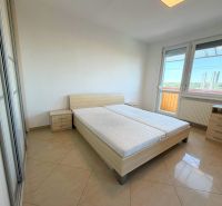 Helles Schlafzimmer in einer Einzimmerwohnung mit Bett, Schrank und Balkon.