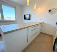 Küche in einer Einzimmerwohnung mit Waschmaschine, weißen Schränken und Arbeitsplatte.