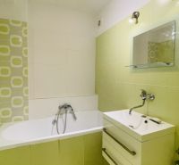 Grün-weißes Badezimmer mit Badewanne und Waschbecken in einer 3-Zimmer-Wohnung.