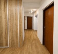 Der Flur in einer 3-Zimmer-Wohnung mit einem Boden in Holzoptik und eingebauten Schränken.
